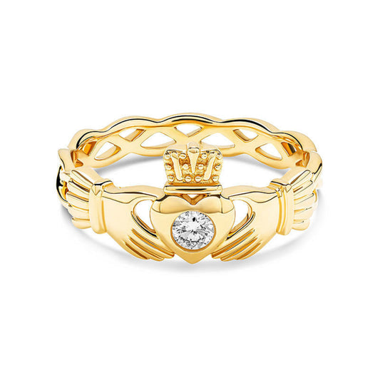 Gold claddagh ring with twisting band and a white diamond center on a white background.