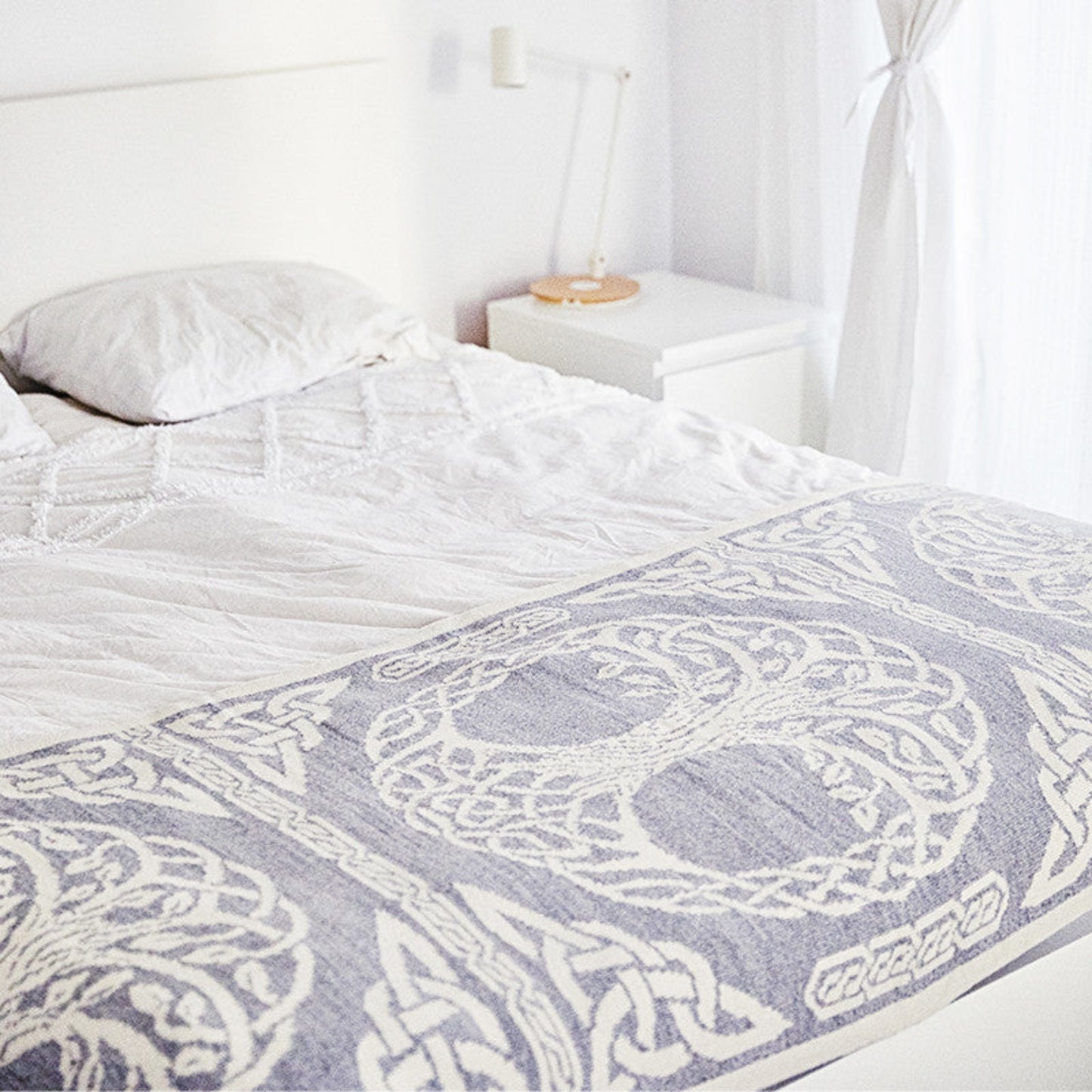 Bed with a patterned gray and white comforter in a bedroom setting.