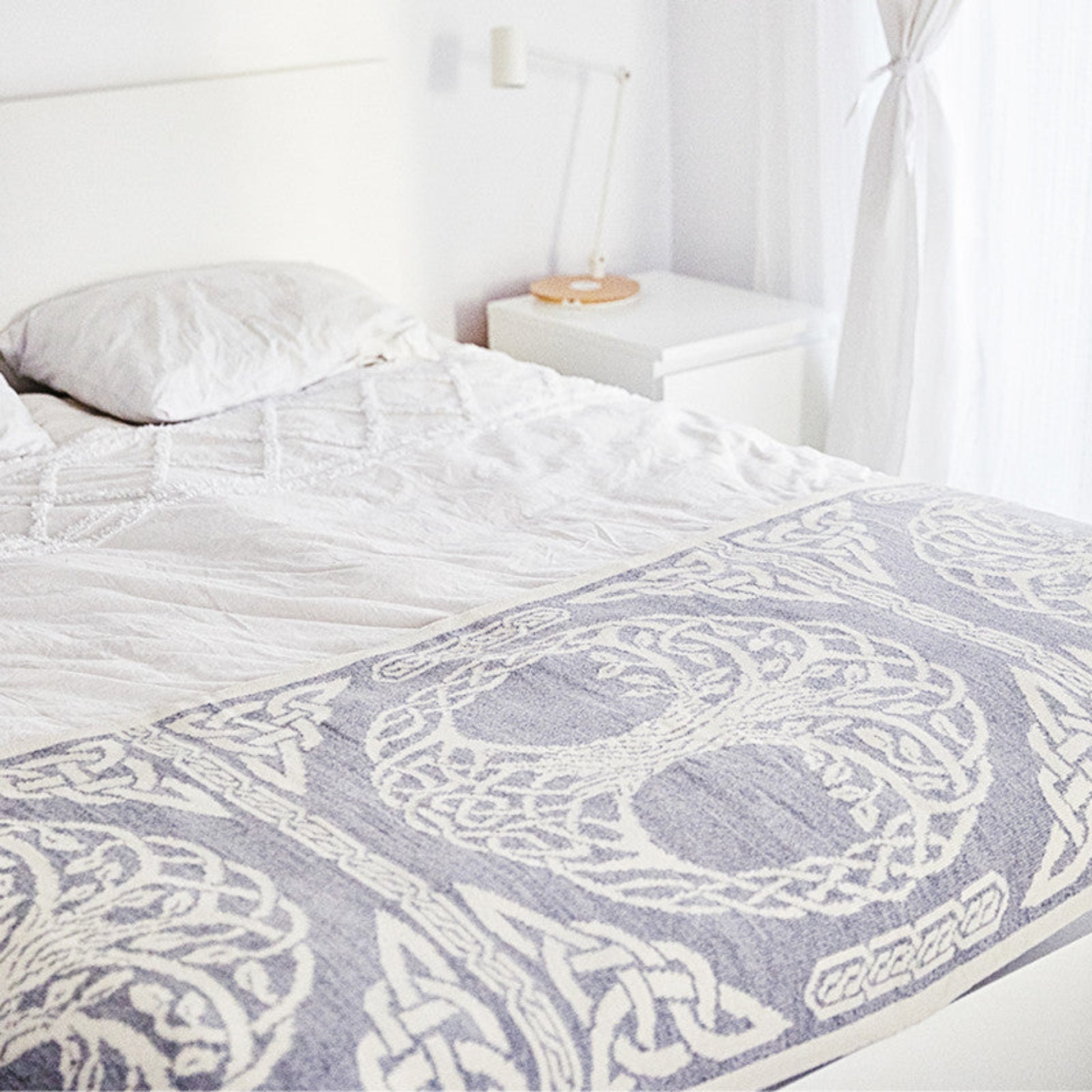 Bed with a patterned gray and white comforter in a bedroom setting.