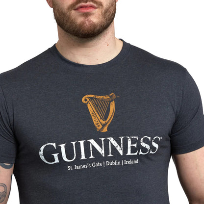 Close-up of a man wearing a grey tee shirt with the word Guinness and a harp printed on the front. 
