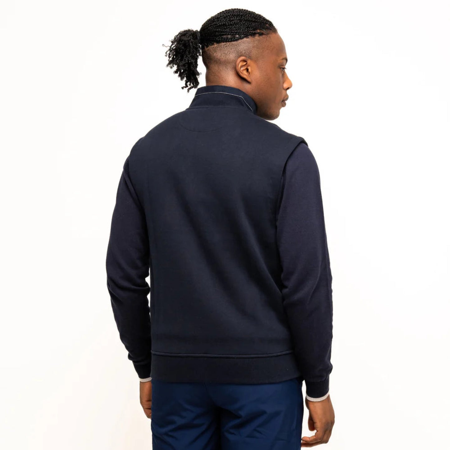 Man facing away in a navy vest. The back is blue and smooth with a high collar.