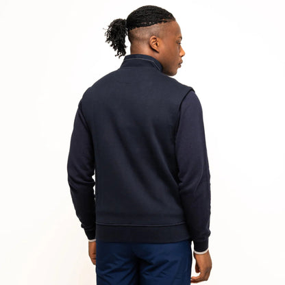 Man facing away in a navy vest. The back is blue and smooth with a high collar.