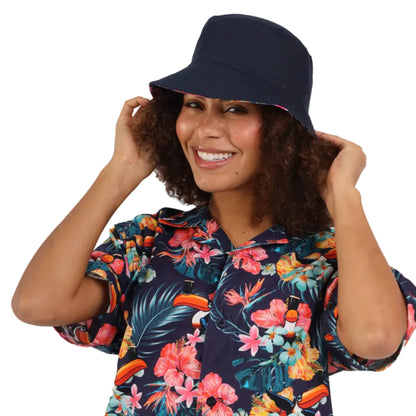 Woman wearing a navy bucket hat and a colorful hawaiian shirt.