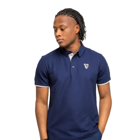 Man wearing a navy-colored polo with a white harp embroidered on one side.