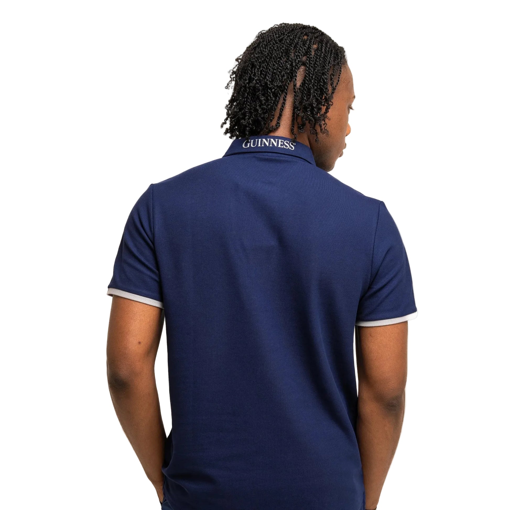 The back of a man wearing a blue polo shirt with "Guinness" written on the back of the collar.