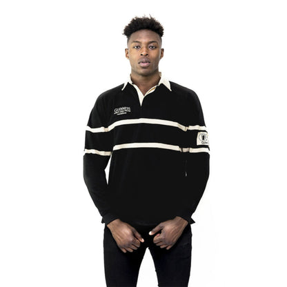 A man wearing a black and cream striped rugby jersey with a collar and a Guinness brand logo on the chest.