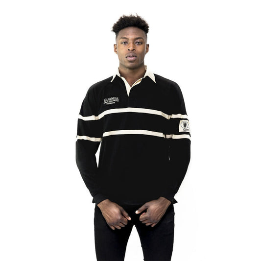 A man wearing a black and cream striped rugby jersey with a collar and a Guinness brand logo on the chest.