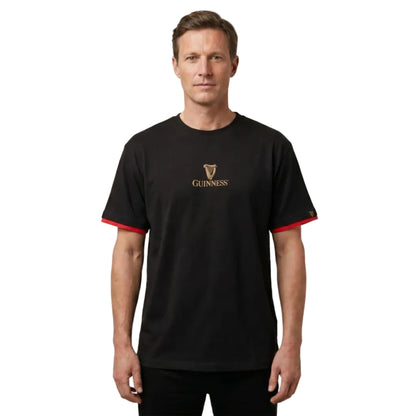 Man wearing a black T-Shirt with red contrast on the sleeves and "Guinness" written on the chest. 