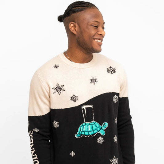 Man wearing a sweater with a turtle design and snowflakes on a white background