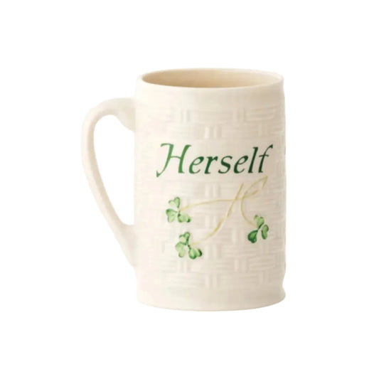A white ceramic mug with green clover designs and the word 'Herself' printed on it.