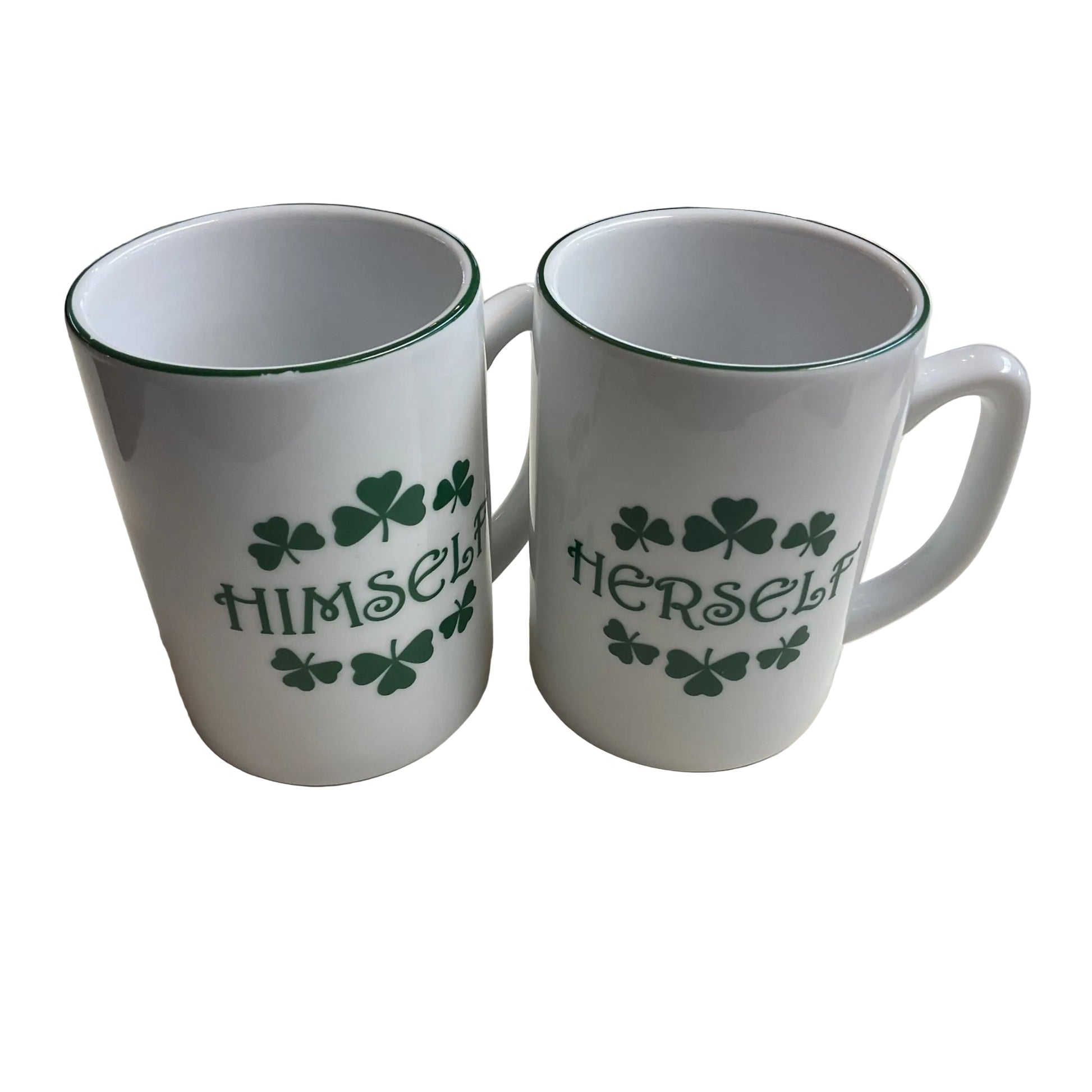 Two white ceramic mugs with green handles and text design, one labeled 'Himself' and the other labeled 'Herself', on a table.