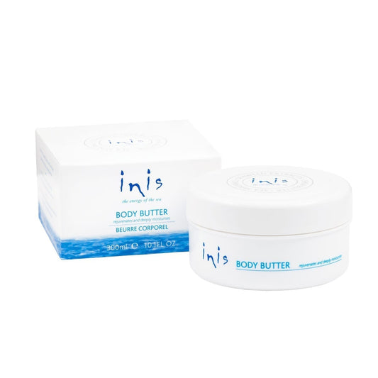 A white jar of Inis body butter next to a square matching box. 