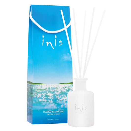 Inis fragrance diffuser glass with reeds next to blue packaging.