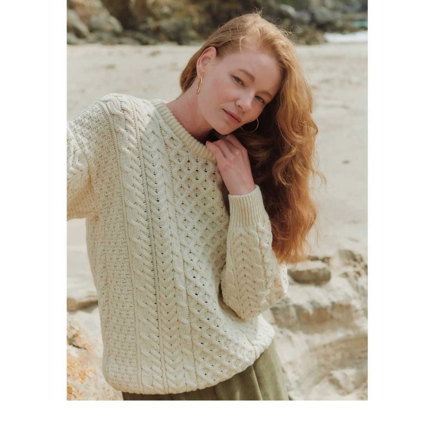 Woman wearing a cream knitted sweater on a beach