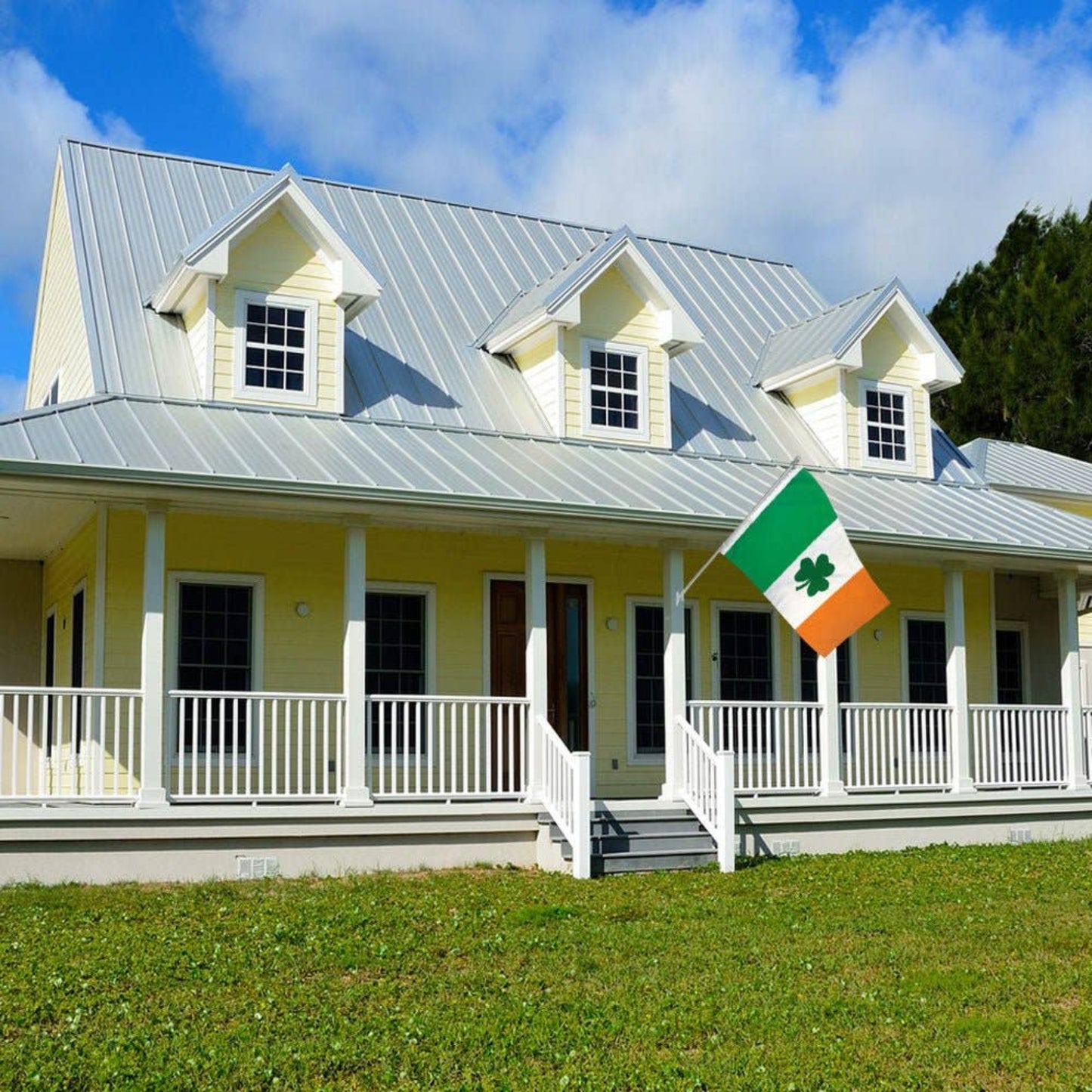 Yellow house with a white porch flying an Irish clover flag. 