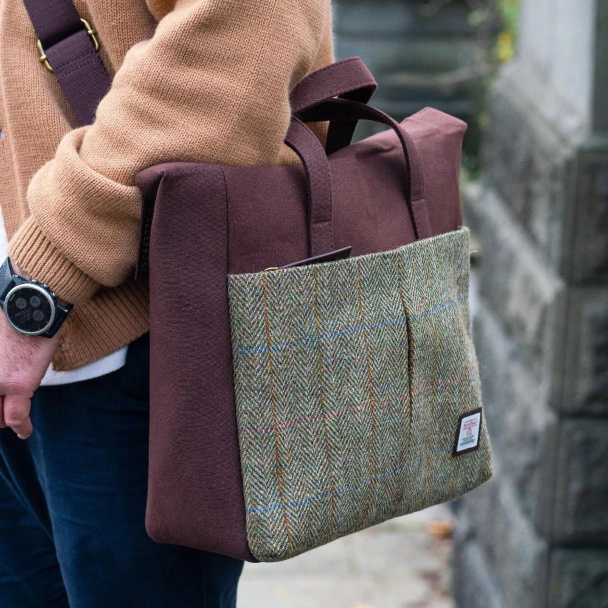 Person holding a brown and plaid bag with a blurred background