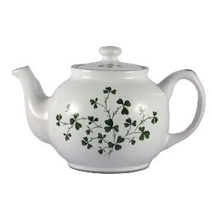 A white ceramic teapot with a green shamrock pattern on the side, featuring a lid and a spout.