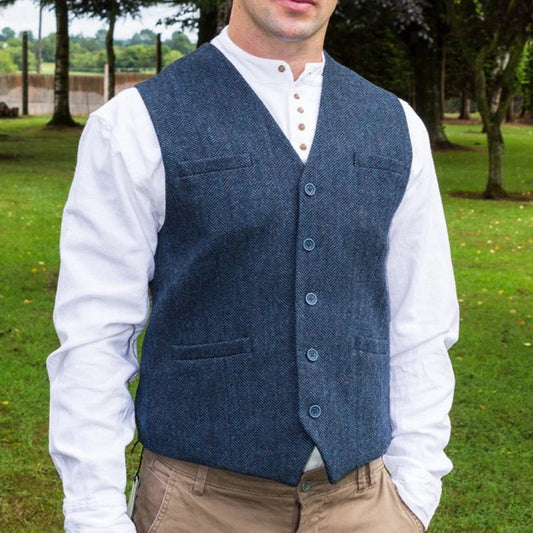 Man wearing a blue vest over a white shirt with a green outdoor background