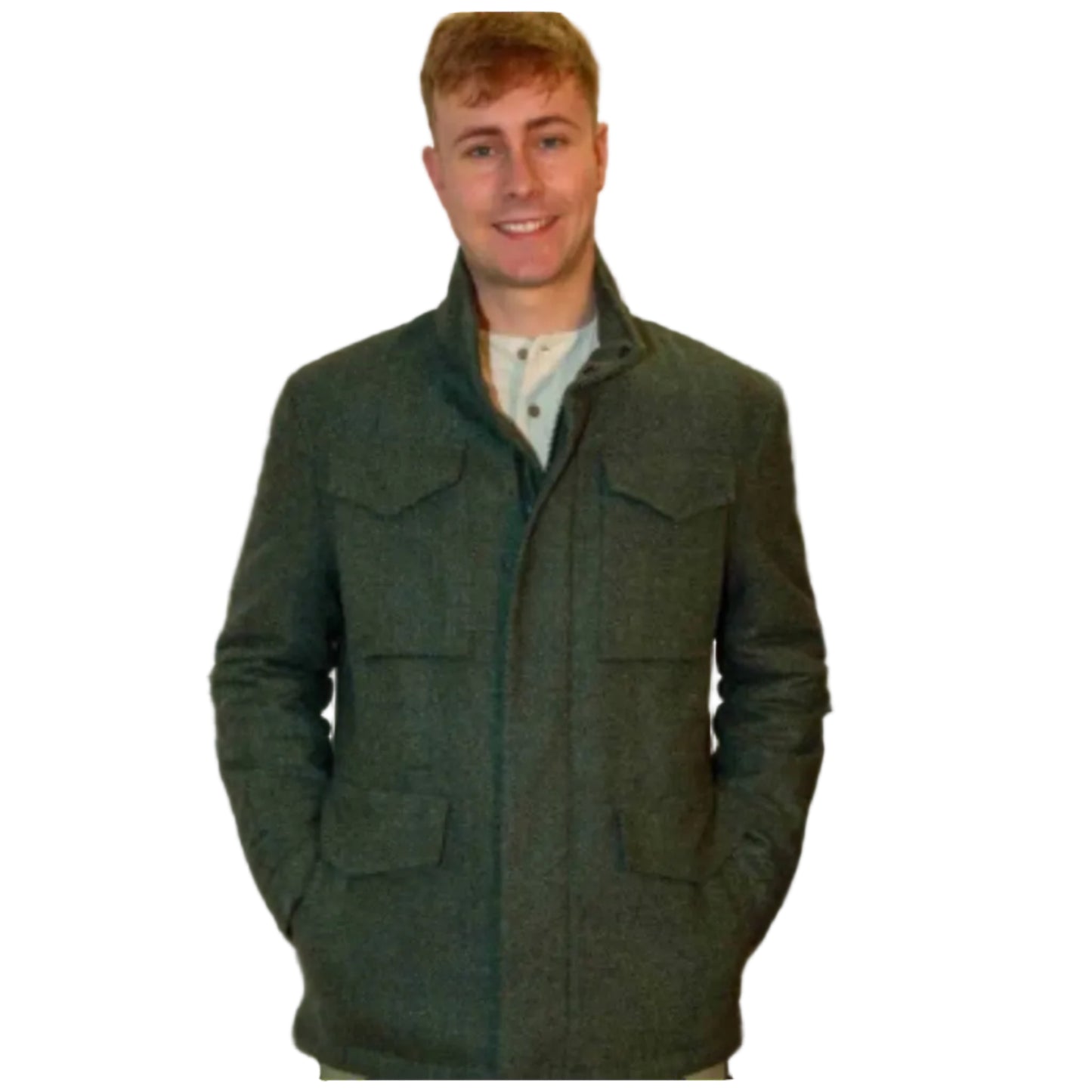 Man wearing a green coat standing in front of a scenic landscape with mountains and water.
