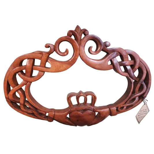 A wooden carving of the Claddagh symbol, featuring intricate designs and a heart shape.