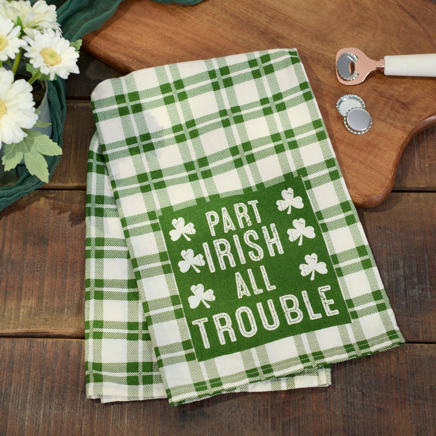 Green and white plaid towel with shamrock design and text on a wooden surface.