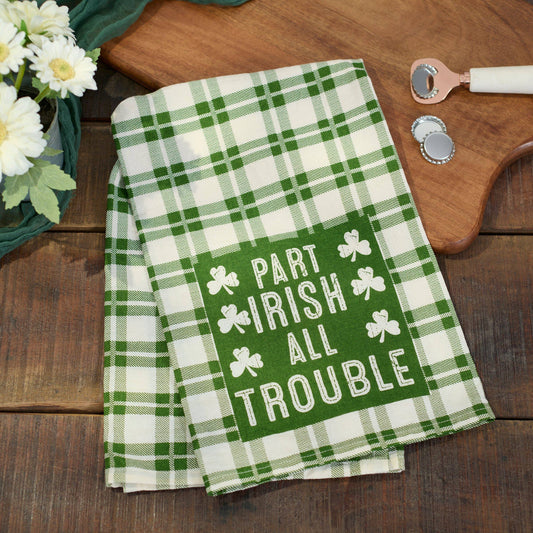 Green and white plaid towel with shamrock design and text on a wooden surface.