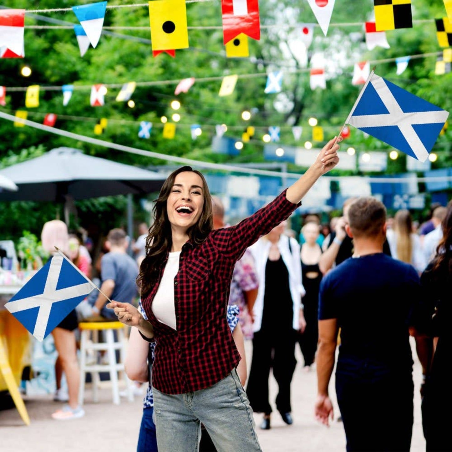 Woman holding a Scottish flag at a festive outdoor event.