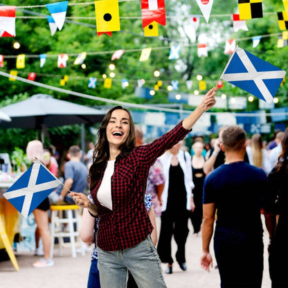 Woman holding a Scottish flag at a festive outdoor event.