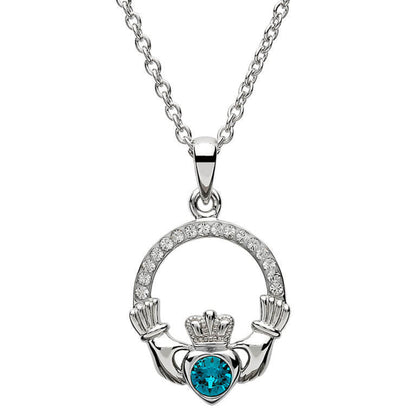 Silver claddagh pendant encrusted with white gems. The heart in the center contains one larger blue gem. 