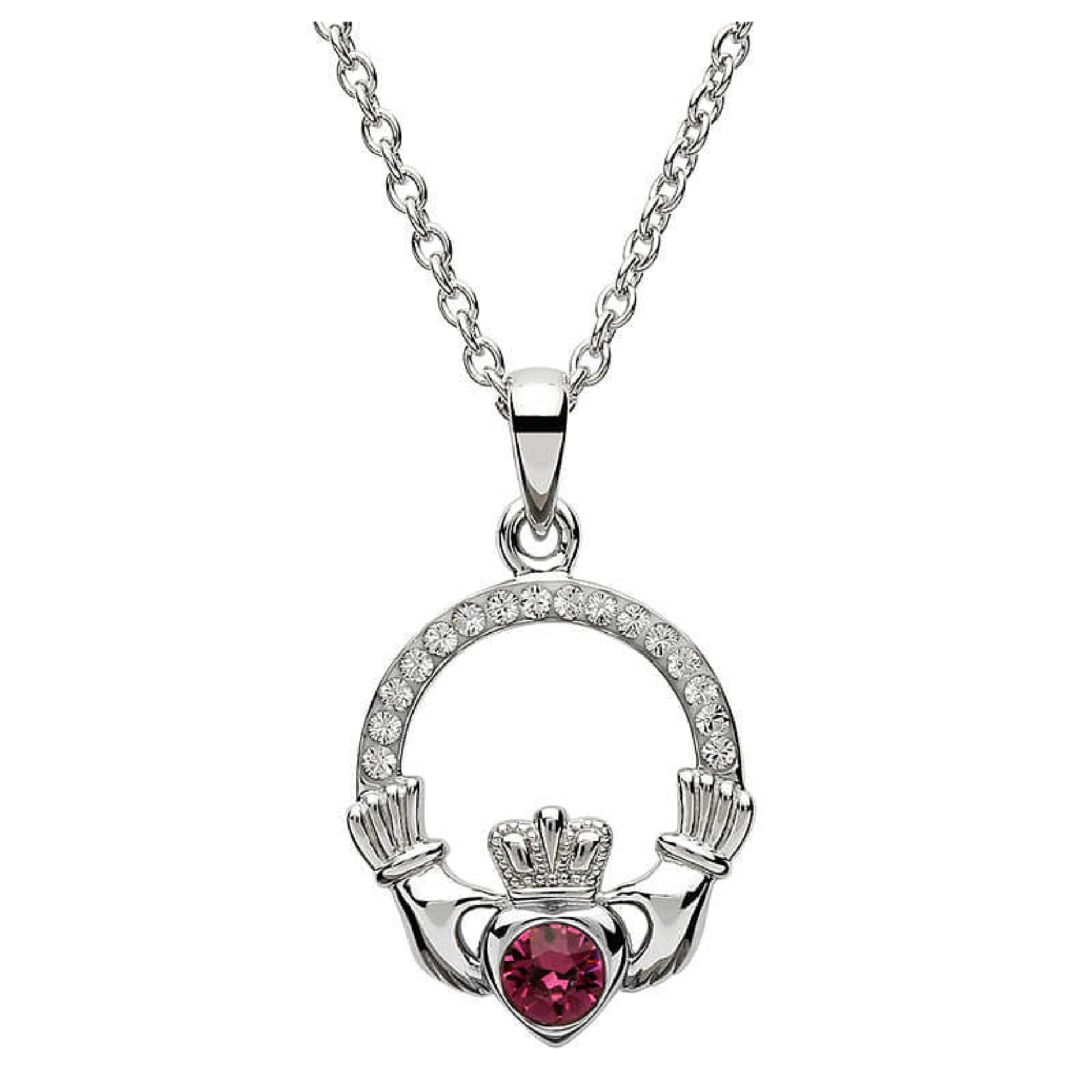 Silver claddagh pendant encrusted with white gems. The heart in the center contains one larger pink gem. 