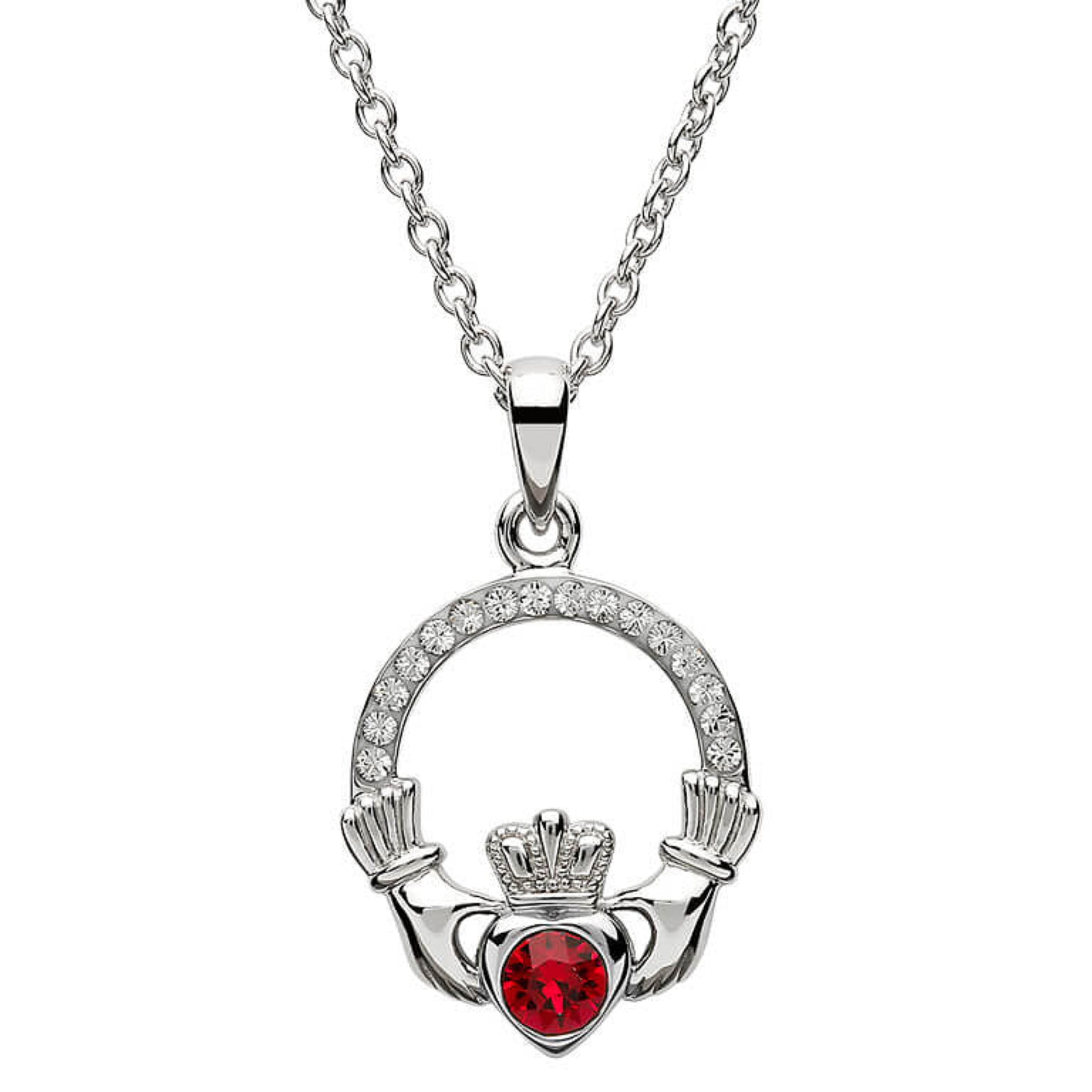Silver claddagh pendant encrusted with white gems. The heart in the center contains one larger red gem. 