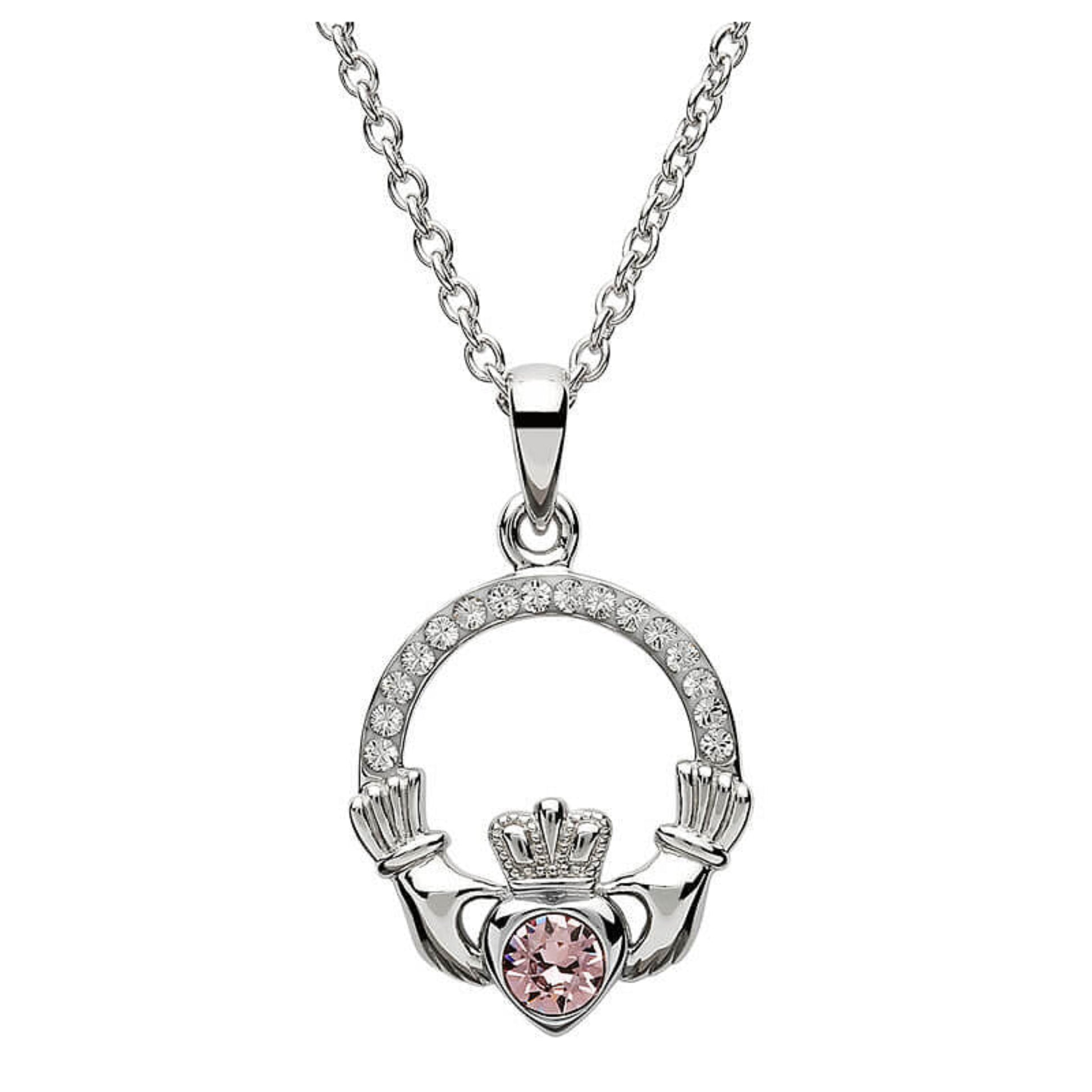 Silver claddagh pendant encrusted with white gems. The heart in the center contains one larger light pink gem. 