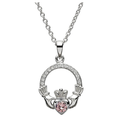 Silver claddagh pendant encrusted with white gems. The heart in the center contains one larger light pink gem. 