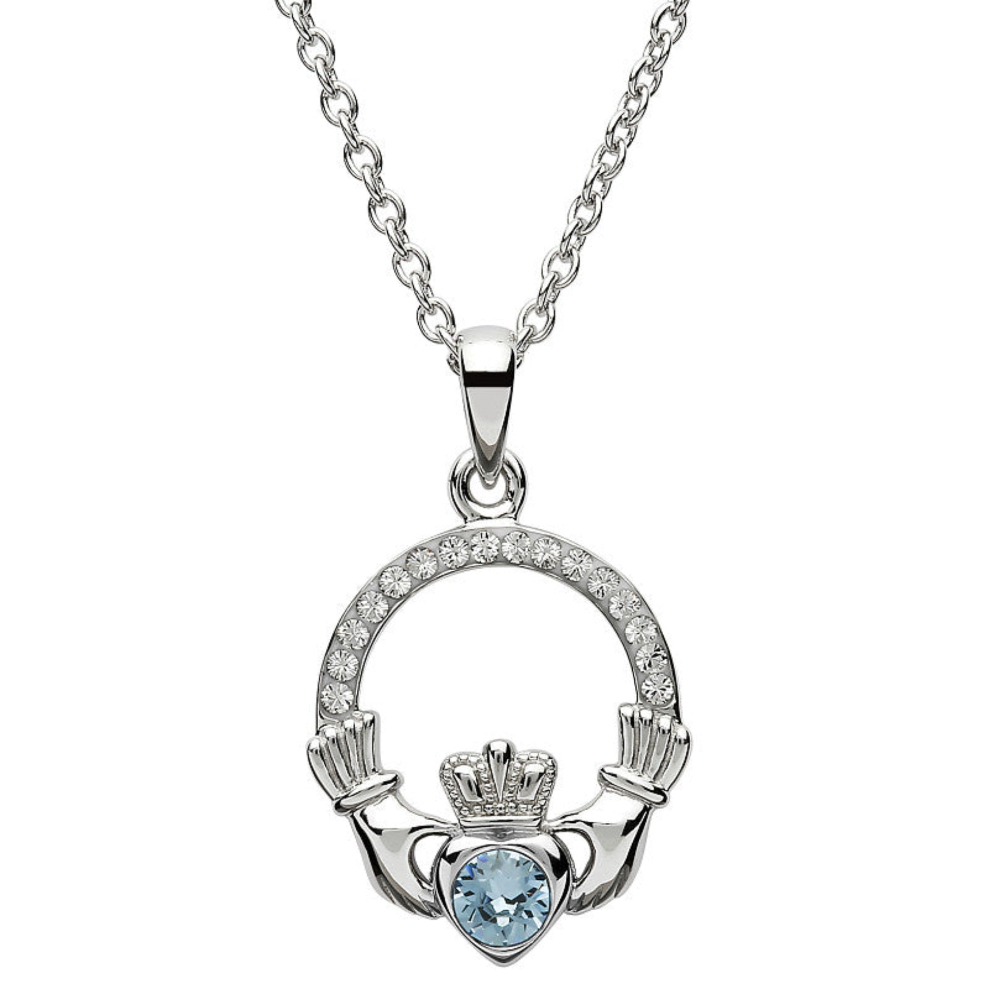 Silver claddagh pendant encrusted with white gems. The heart in the center contains one larger light blue gem. 