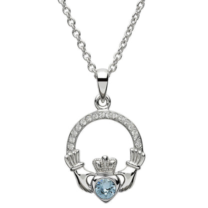 Silver claddagh pendant encrusted with white gems. The heart in the center contains one larger light blue gem. 