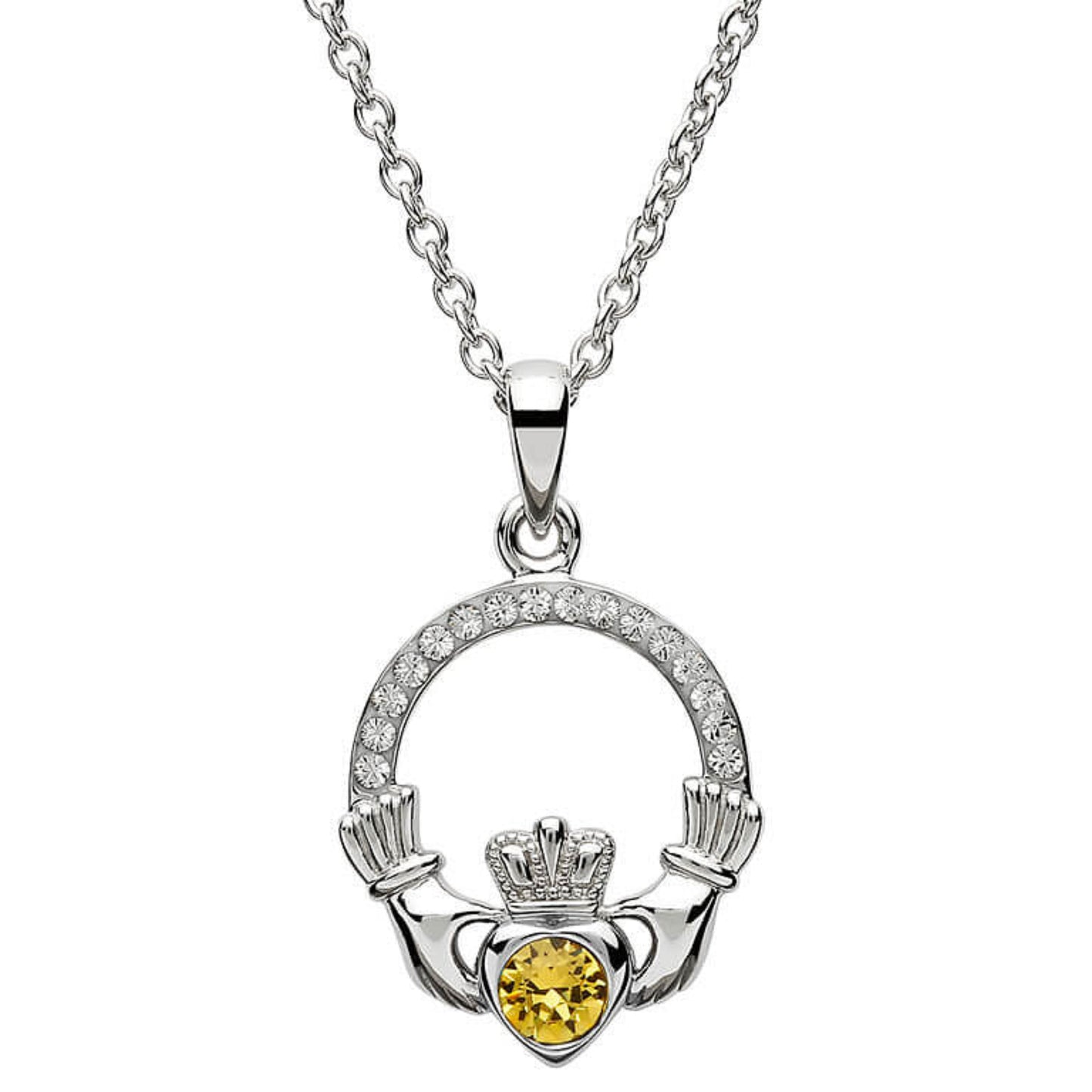 Silver claddagh pendant encrusted with white gems. The heart in the center contains one larger light orange gem. 