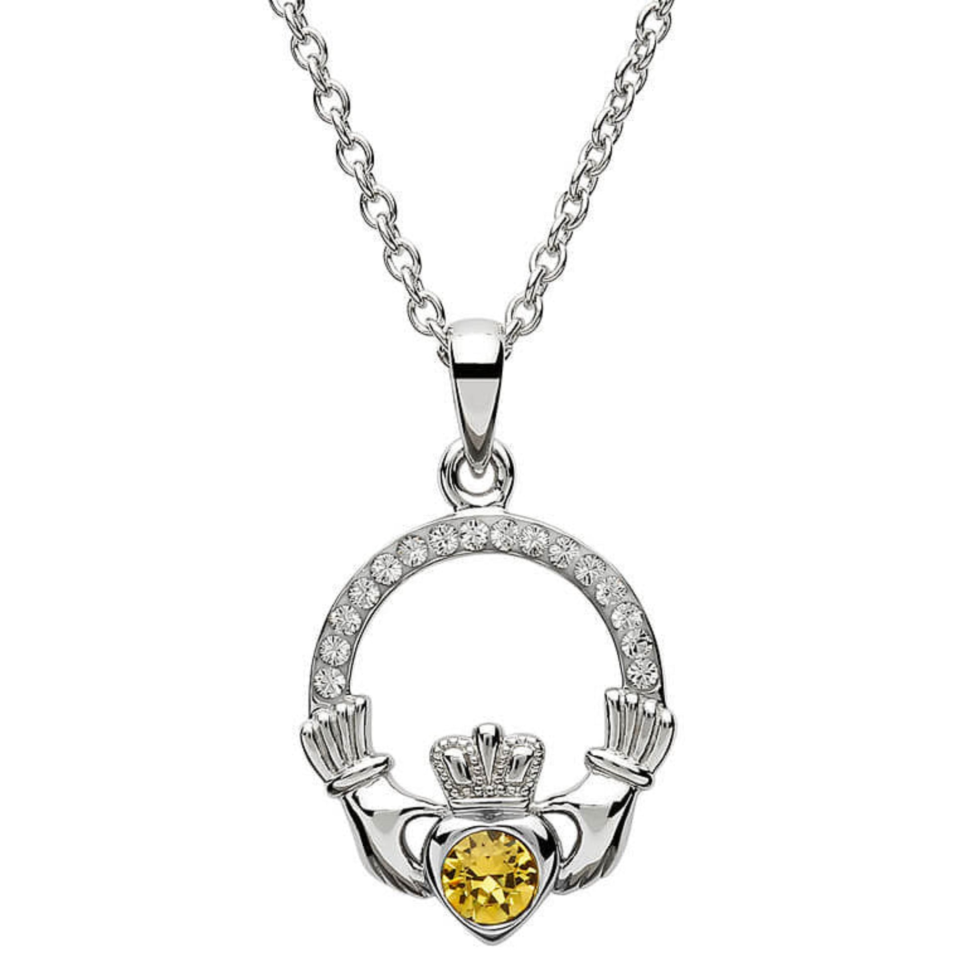 Silver claddagh pendant encrusted with white gems. The heart in the center contains one larger light orange gem. 