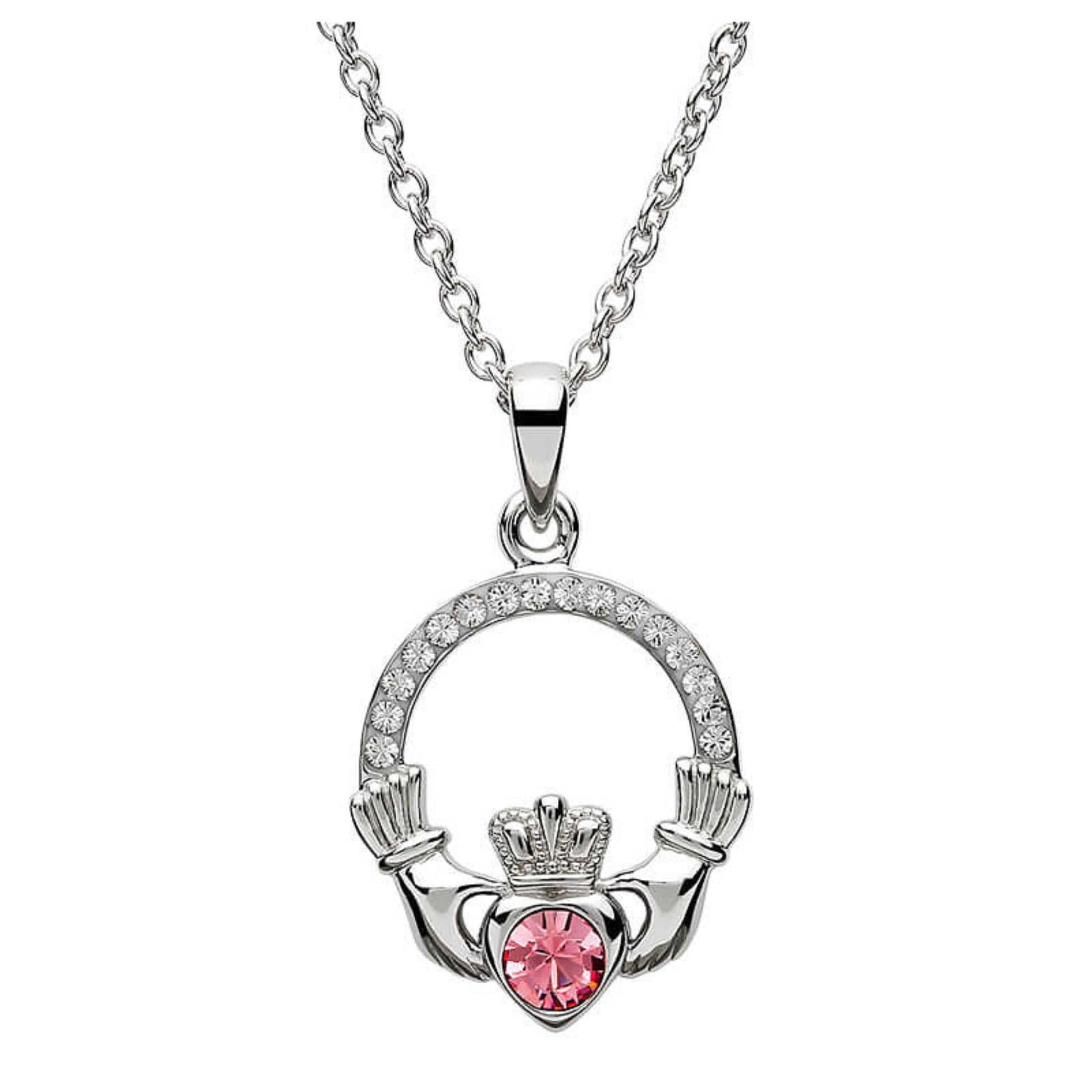 Silver claddagh pendant encrusted with white gems. The heart in the center contains one larger pink gem. 