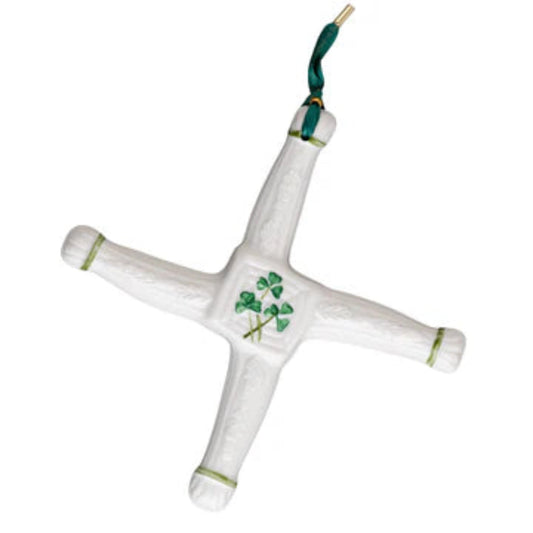 A ceramic St. Brigid's Day cross with a white glaze and green decorations, featuring a shamrock in the center, displayed against a plain background.