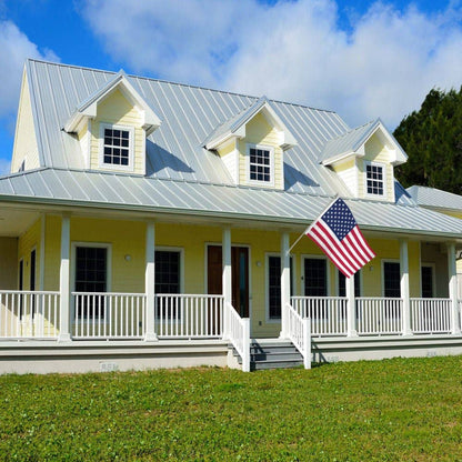 Yellow house with a white porch flying an American flag. 
