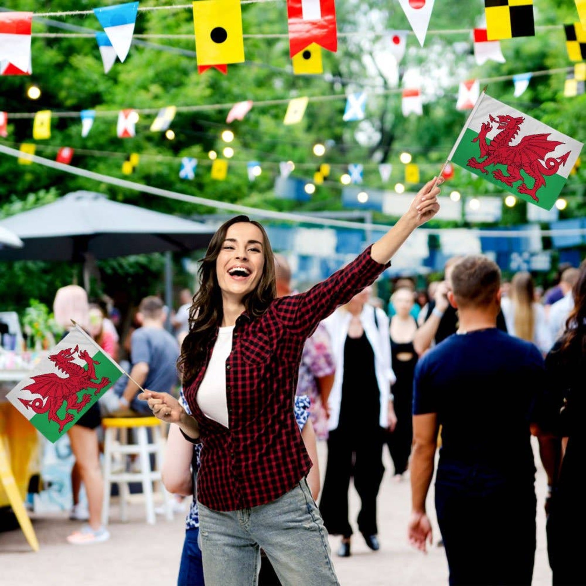 Woman holding a Welsh flag at an outdoor event.