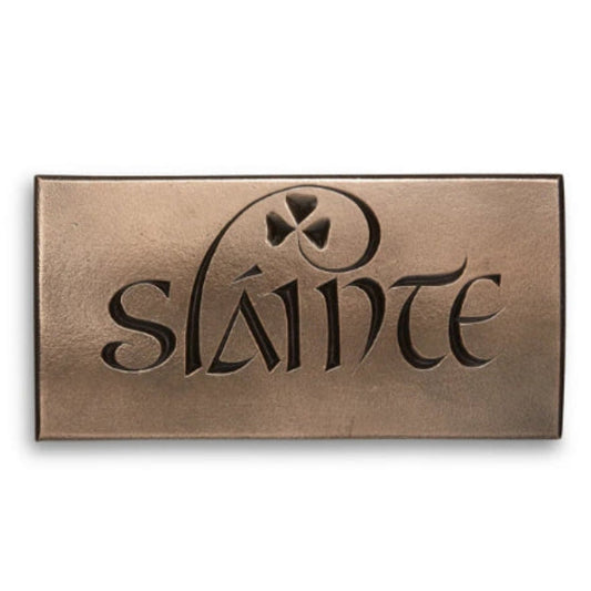 A bronze rectangular plaque with the word "Slainte" engraved into it. The L curls to become a shamrock