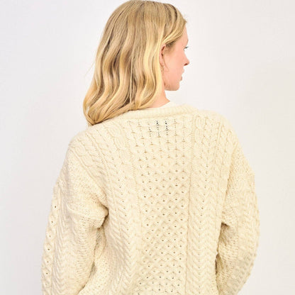 Woman wearing a cream knitted sweater against a white background