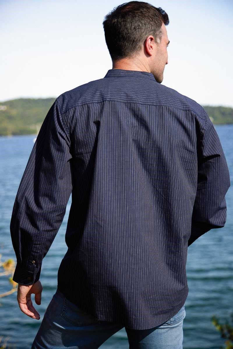 Man wearing a dark blue striped shirt by a body of water