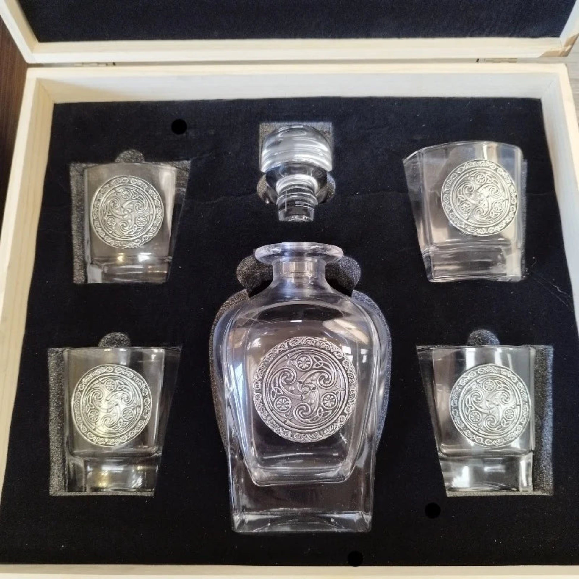 An elegant Mullingar Pewter decanter set displayed in a distressed wood-effect box, including a crystal decanter and four matching glasses, all adorned with pewter designs.