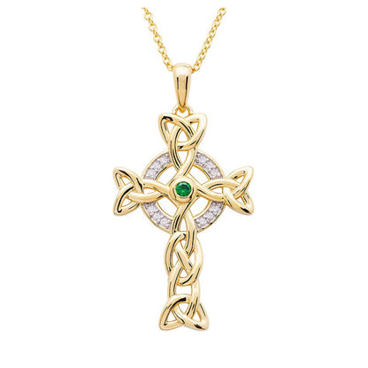 A gold Celtic cross necklace with white cubic zirconias and a central green emerald stone on a chain.
