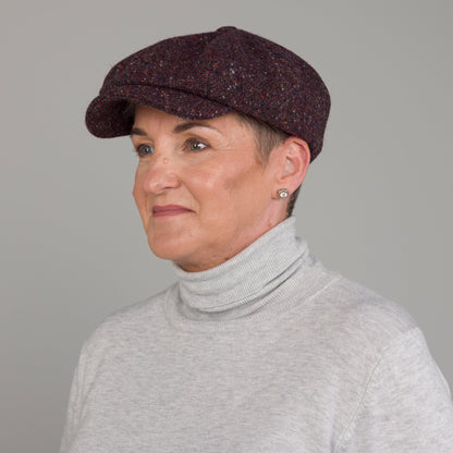 Woman wearing a dark brown cap and gray turtleneck against a plain background