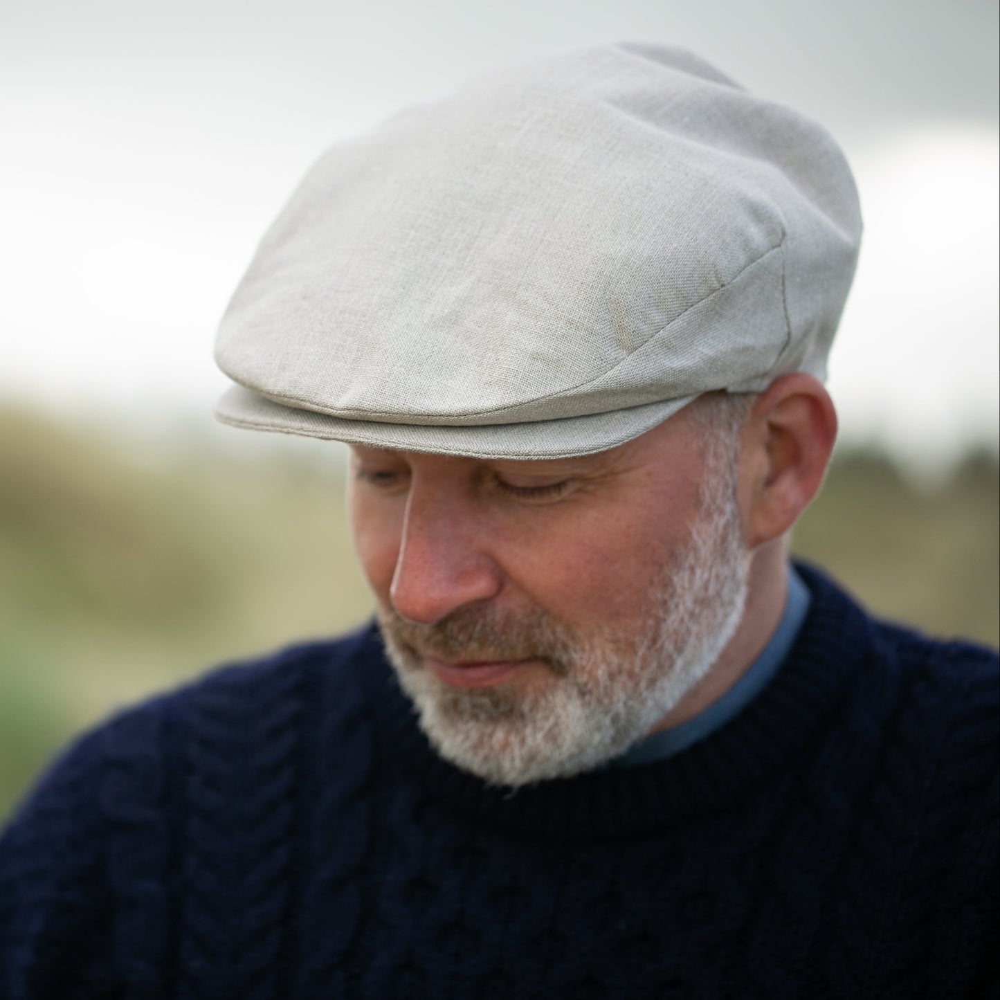 Man wearing a flat cap with a blurred natural background