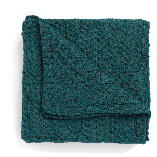 Folded teal knitted blanket on a white background