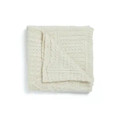 Folded cream-colored textured blanket on a white background